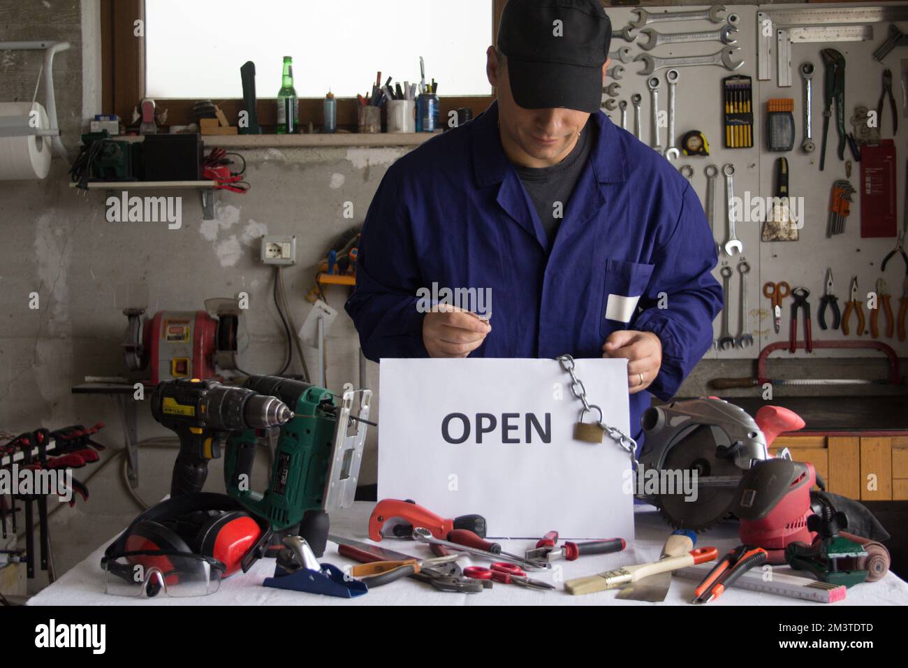 Craftsman in his with work tools in front of him and a sign