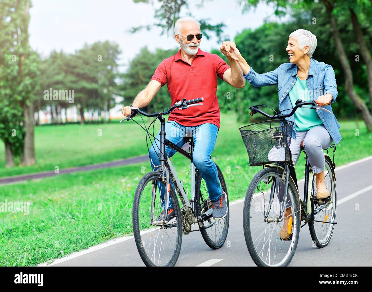 senior couple happy elderly love together retirement bicycle bike man woman mature fun Stock Photo