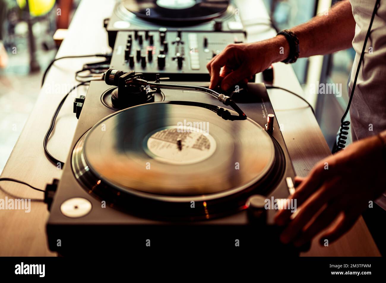 Dj hands on equipment deck and mixer with vinyl record at party, human