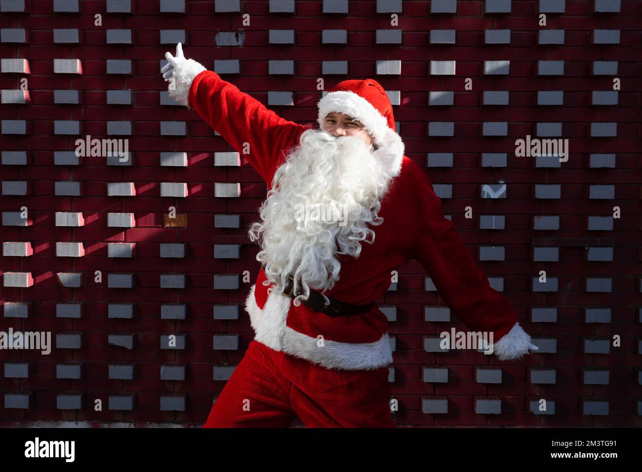 Santa Claus in the dancing pose in front of a red and white wall Stock ...