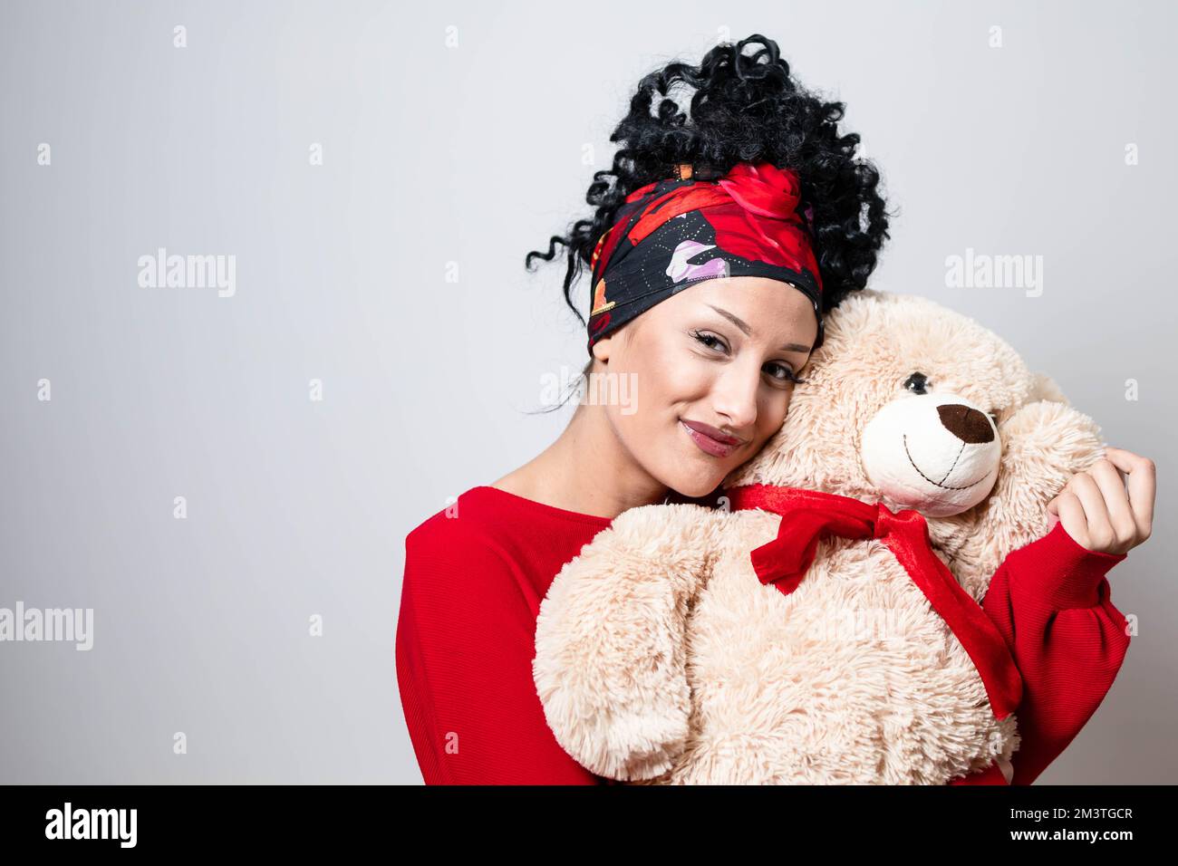 Beautiful curly young girl with bandana hairstyle holding teddy bear Stock Photo