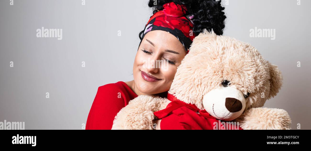Beautiful curly young girl with bandana hairstyle holding teddy bear. Wide, banner format Stock Photo