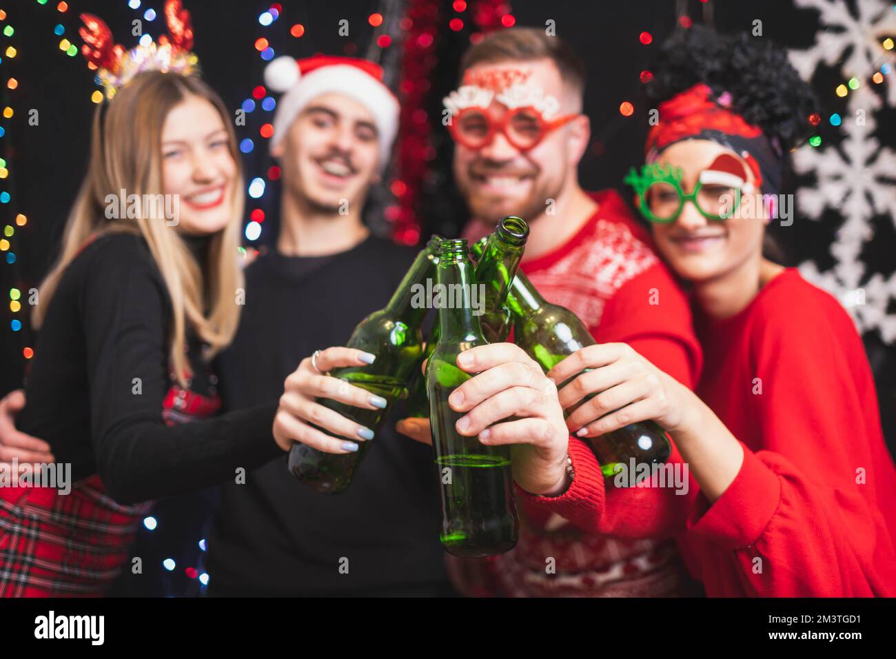 Four friends celebrating New year toasting with beer bottles. Focus on bottles Stock Photo