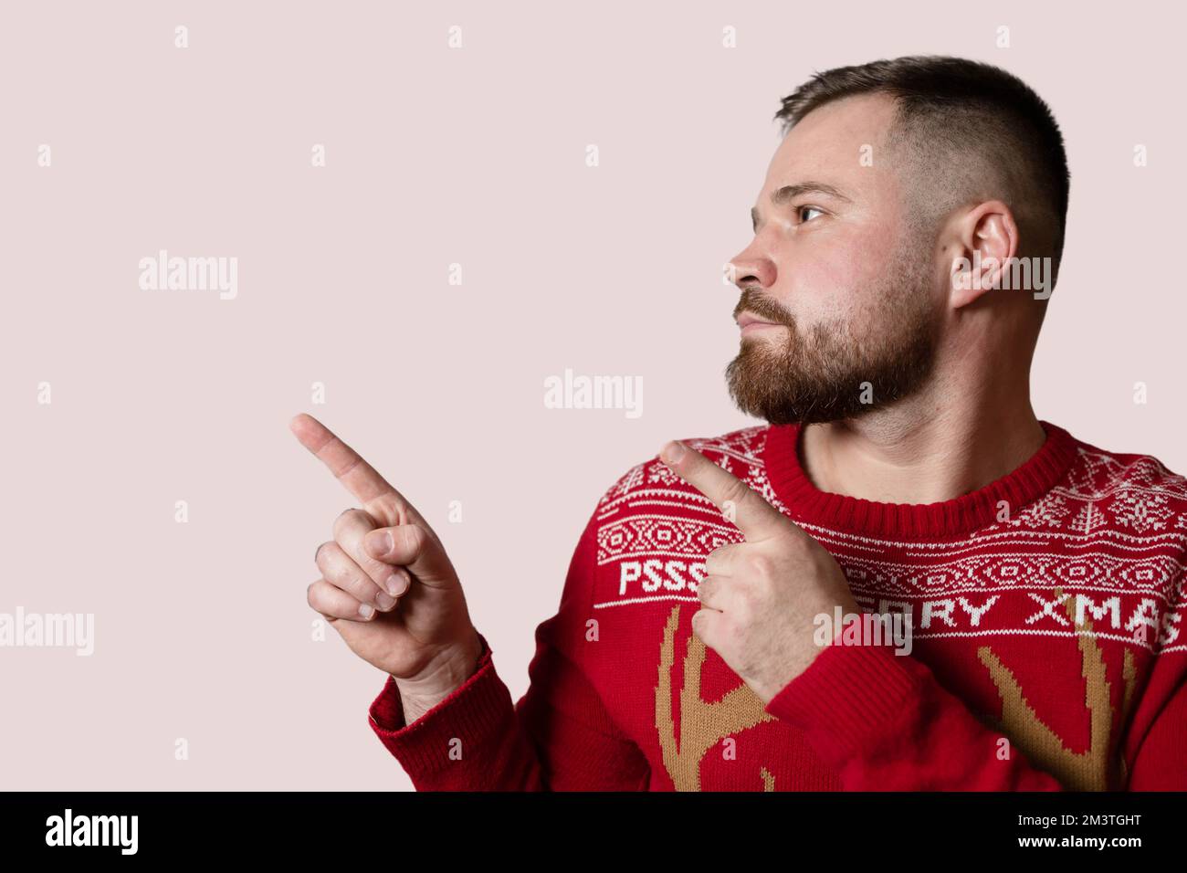 Young, bearded man showing something. Empty space, isolated on red background Stock Photo