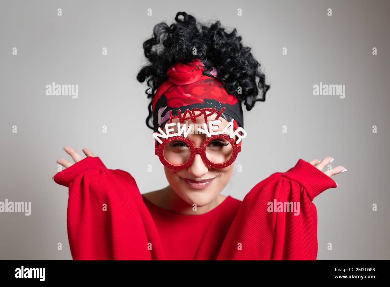 Beautiful curly young girl with New year prop glasses and bandana hairstyle Stock Photo