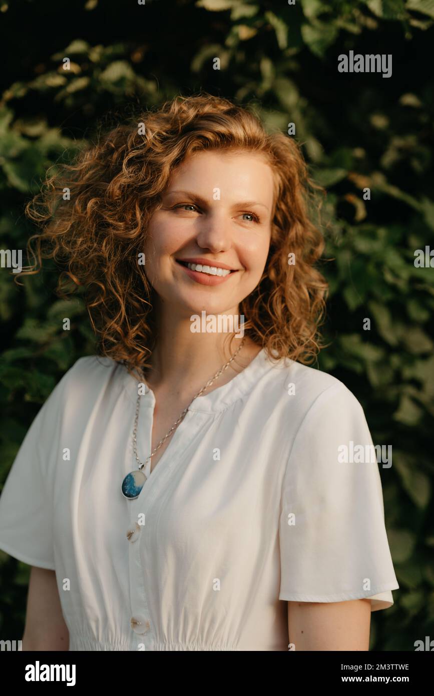 A woman with curly hair is posing in the park at the sunset Stock Photo ...