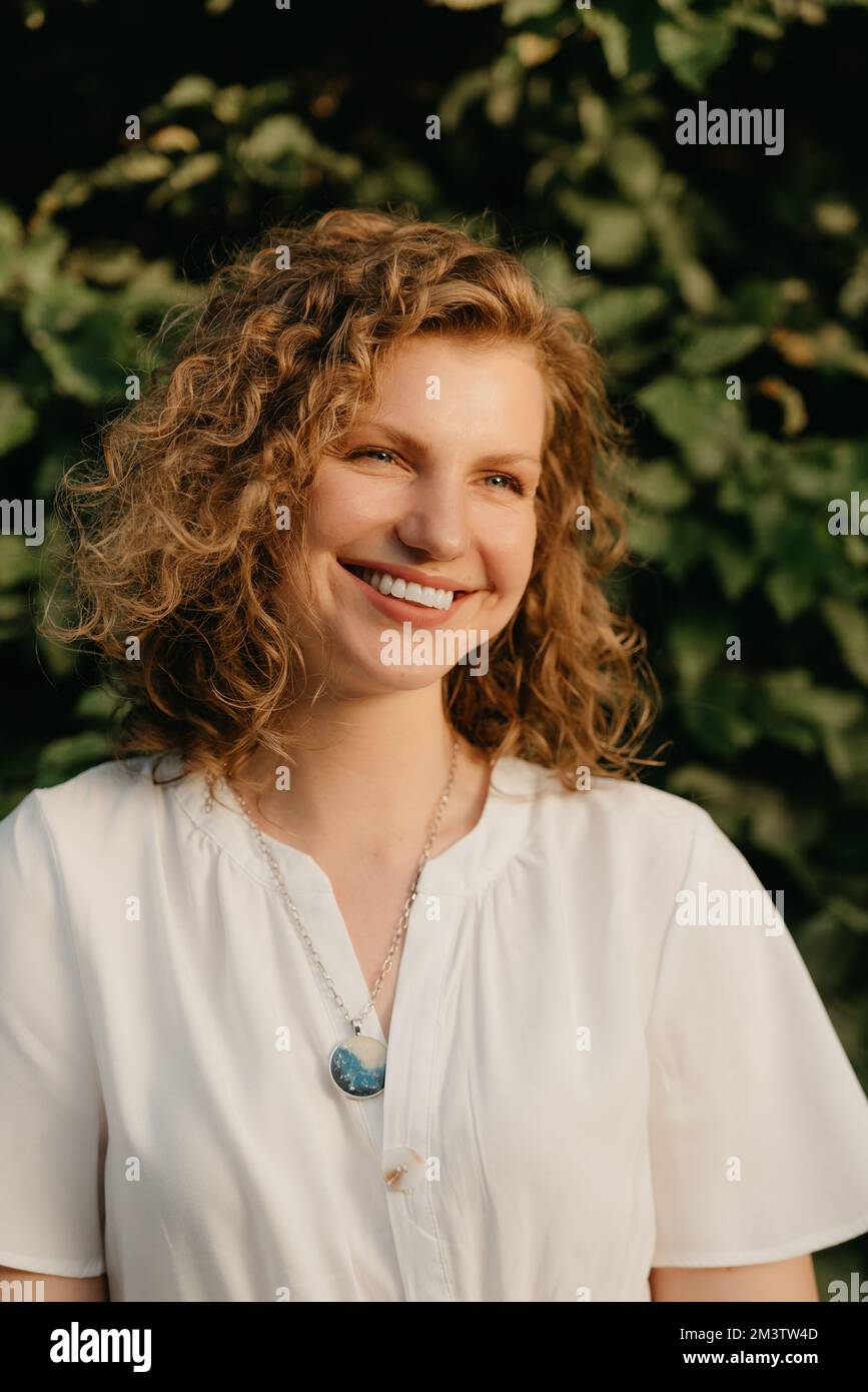 A woman with curly hair is posing in the park at the sunset Stock Photo ...