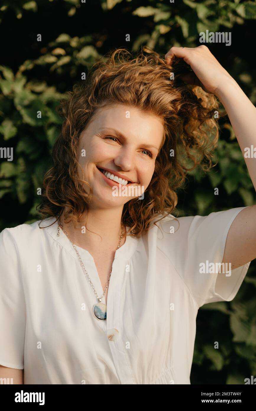 A woman with curly hair is posing in the park at the sunset Stock Photo ...