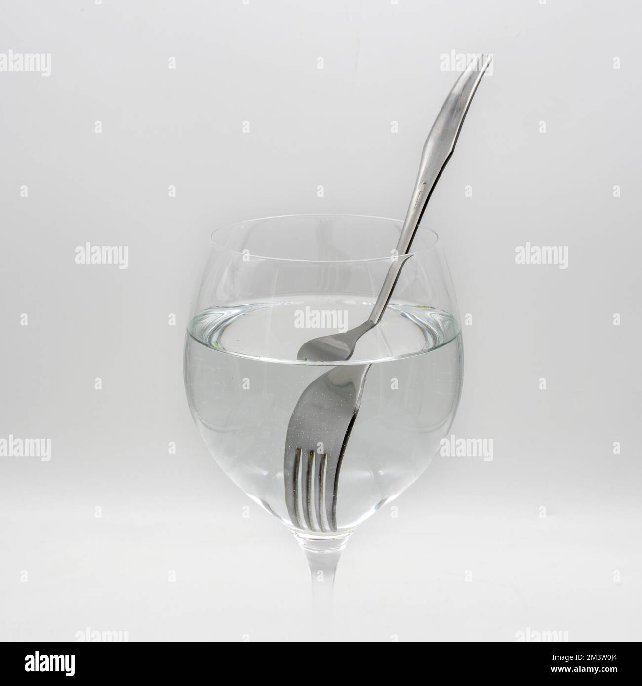 Vista de un tenedor distorsionado dentro de una vaso lleno de agua, demostrando la refracción de la luz Stock Photo