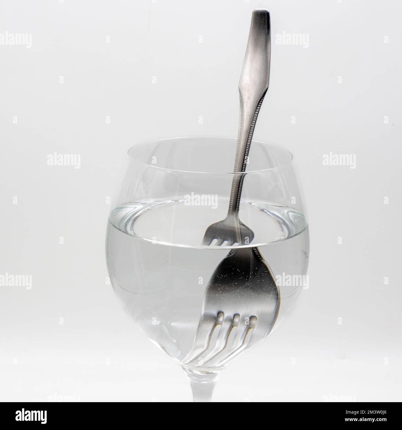 Vista de un tenedor distorsionado dentro de una vaso lleno de agua, demostrando la refracción de la luz Stock Photo