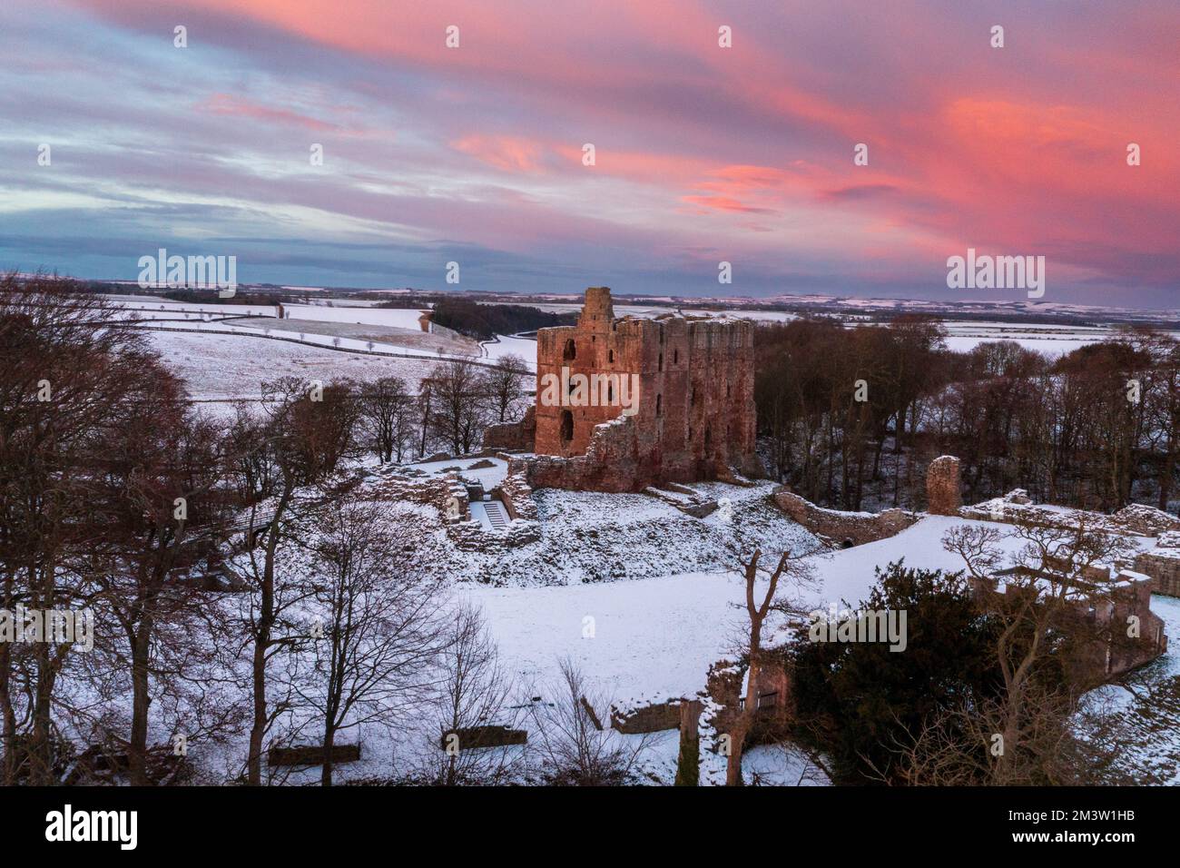 Norham Castle guarding the Scottish border high above the River Tweed as the sunsets over a winter landscape. Norham, Northumberland, England, UK Stock Photo