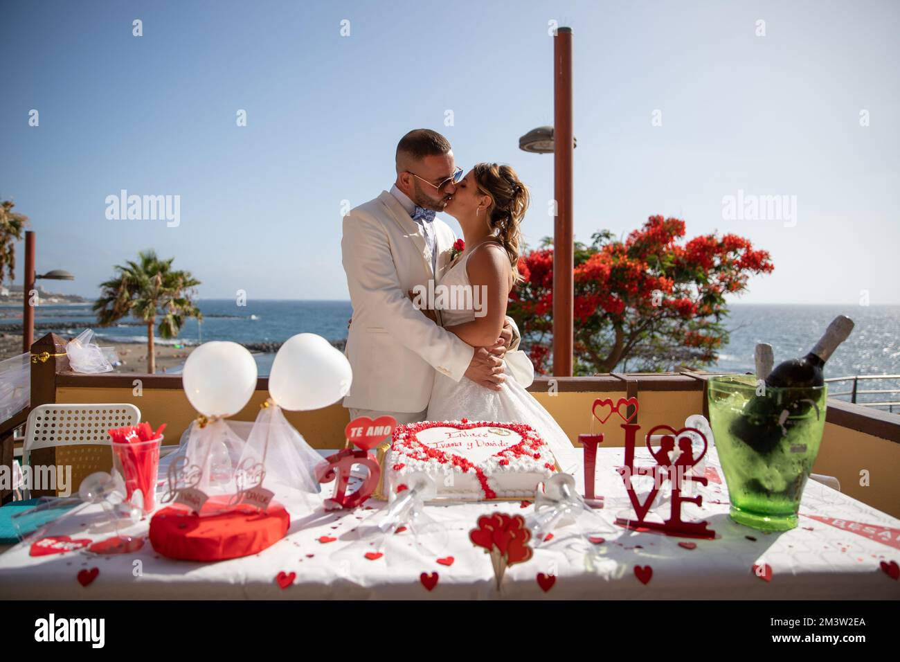 Newlyweds couple kisses in front of the wedding cake, passionate moment Stock Photo