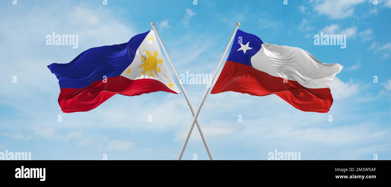 two crossed flags Chile and Philippines waving in wind at cloudy sky ...