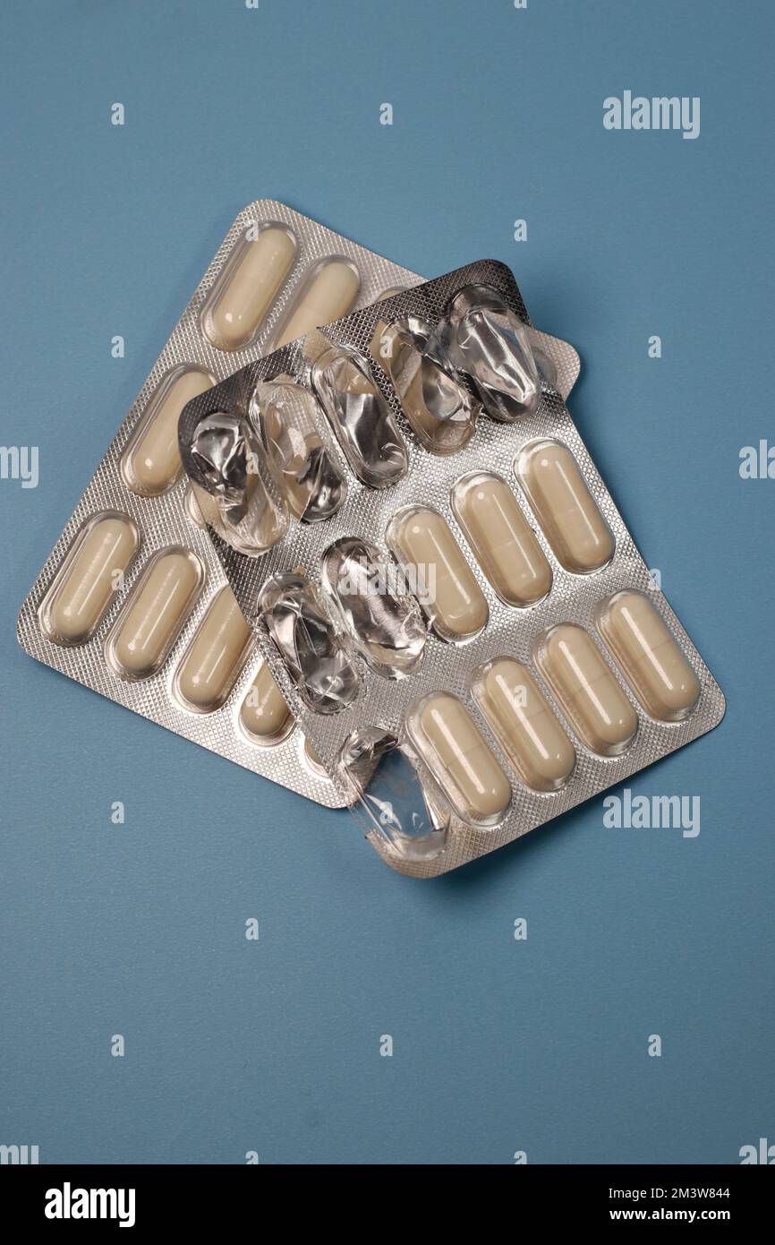 close up of white pills capsules on blue background, top view Stock Photo