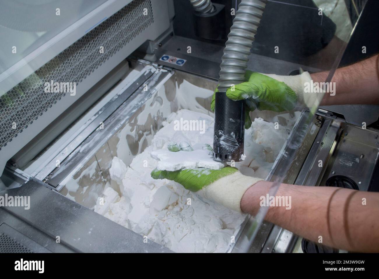 Mane taking out models from white polyamide powder in working chamber ...
