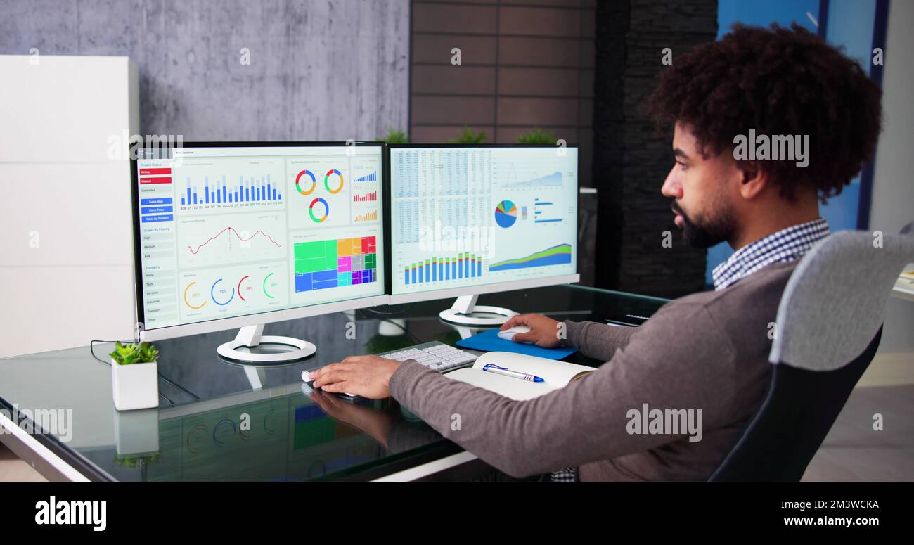 African Data Analyst Man Using Spreadsheet On Computer Stock Photo