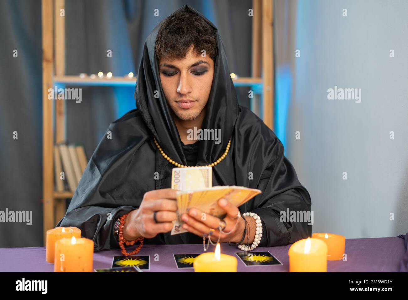 fortune teller man reading tarot cards on a table with candles. Stock Photo