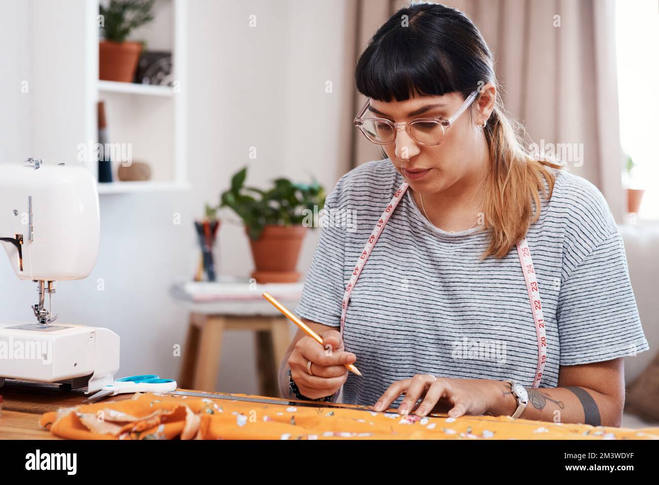 I have to measure this so itll be perfect for sewing. a young woman designing a garment at home. Stock Photo