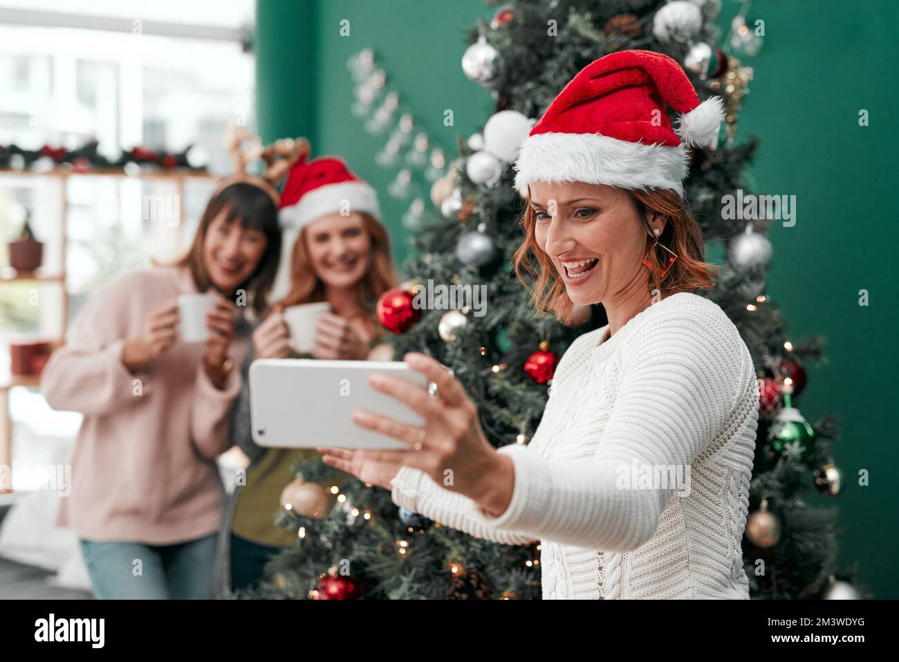 We did good this year. three attractive women taking Christmas selfies together at home. Stock Photo