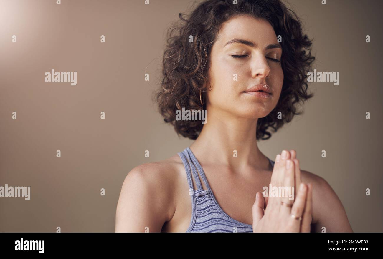 Feeling balanced and at peace. an attractive young woman sitting alone and meditating indoors. Stock Photo