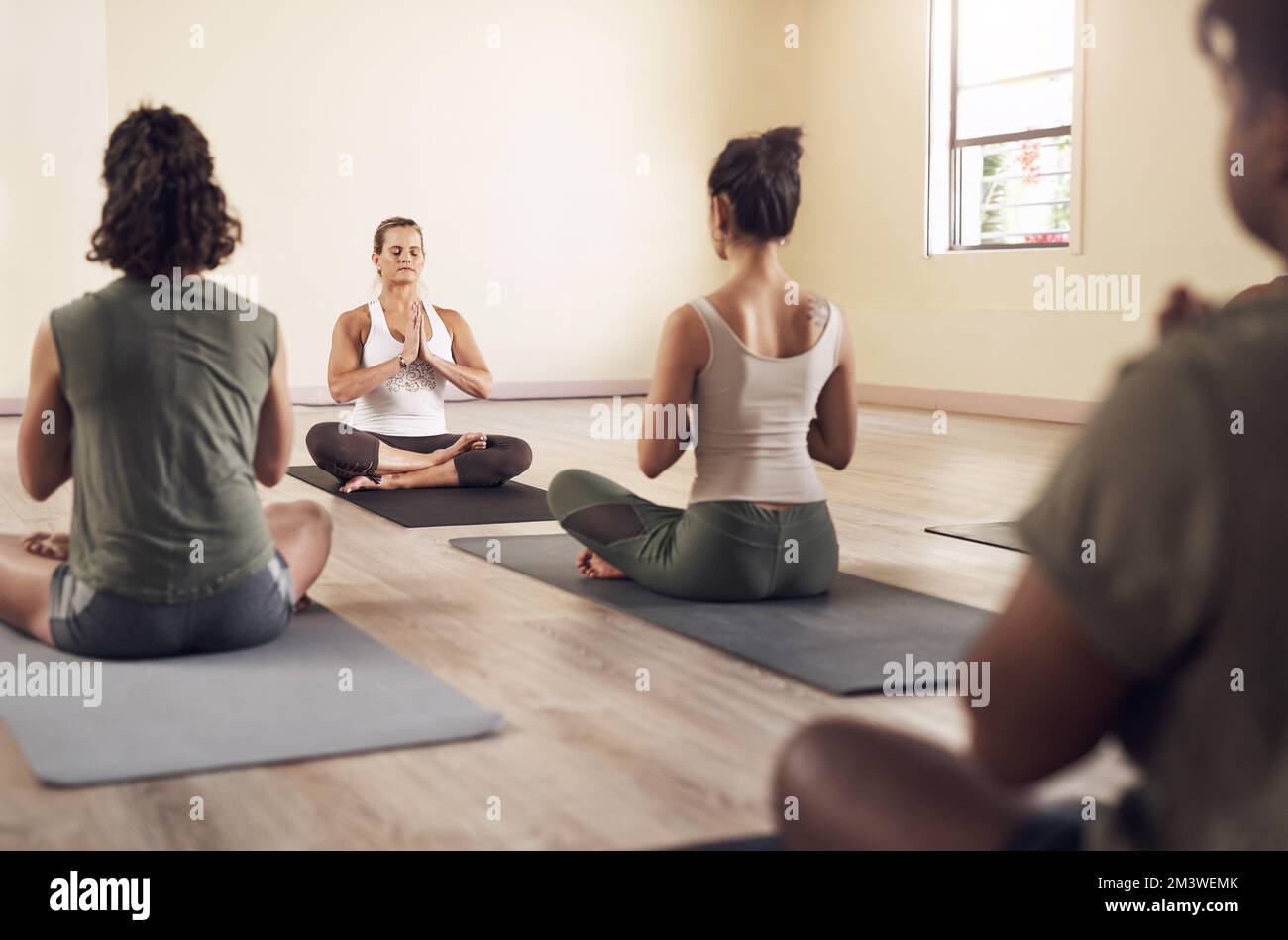 Close your eyes and let the zen take over. a group of young people meditating and working out together in a yoga class. Stock Photo