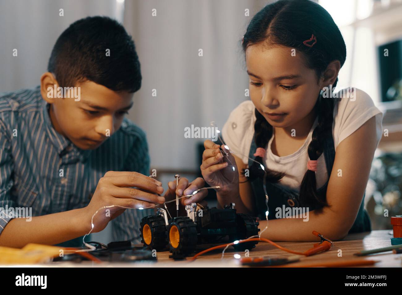 Their technical skills are already at a high level. two adorable young siblings building a robotic toy car together at home. Stock Photo