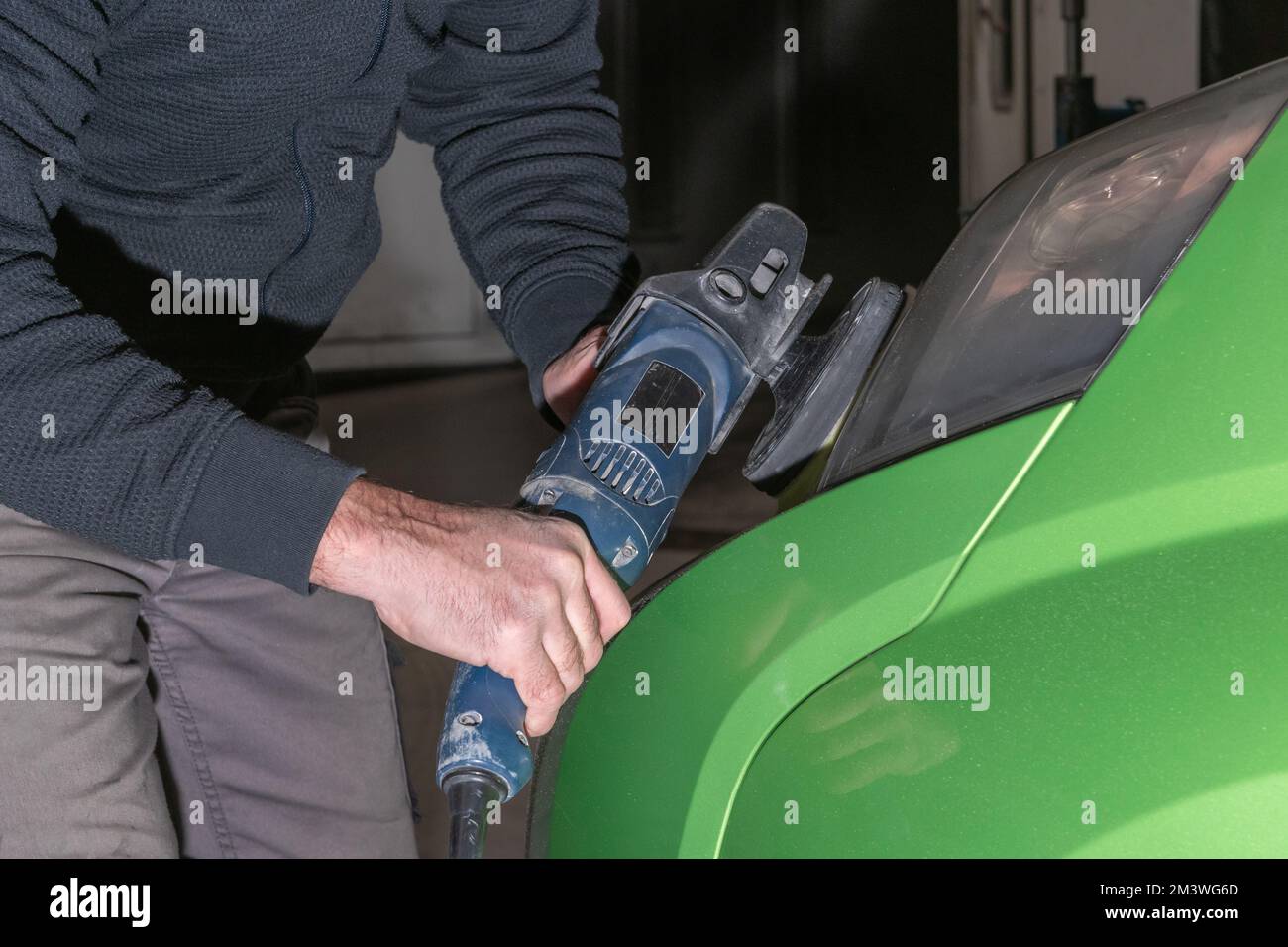 Polishing car headlights. Car service worker with electrical polisher polishing car Stock Photo