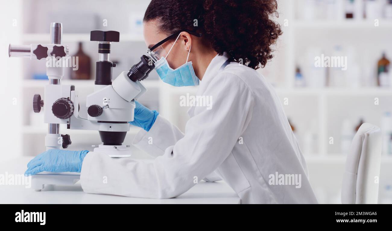 Testing some new samples. a young scientist using a microscope in a lab. Stock Photo