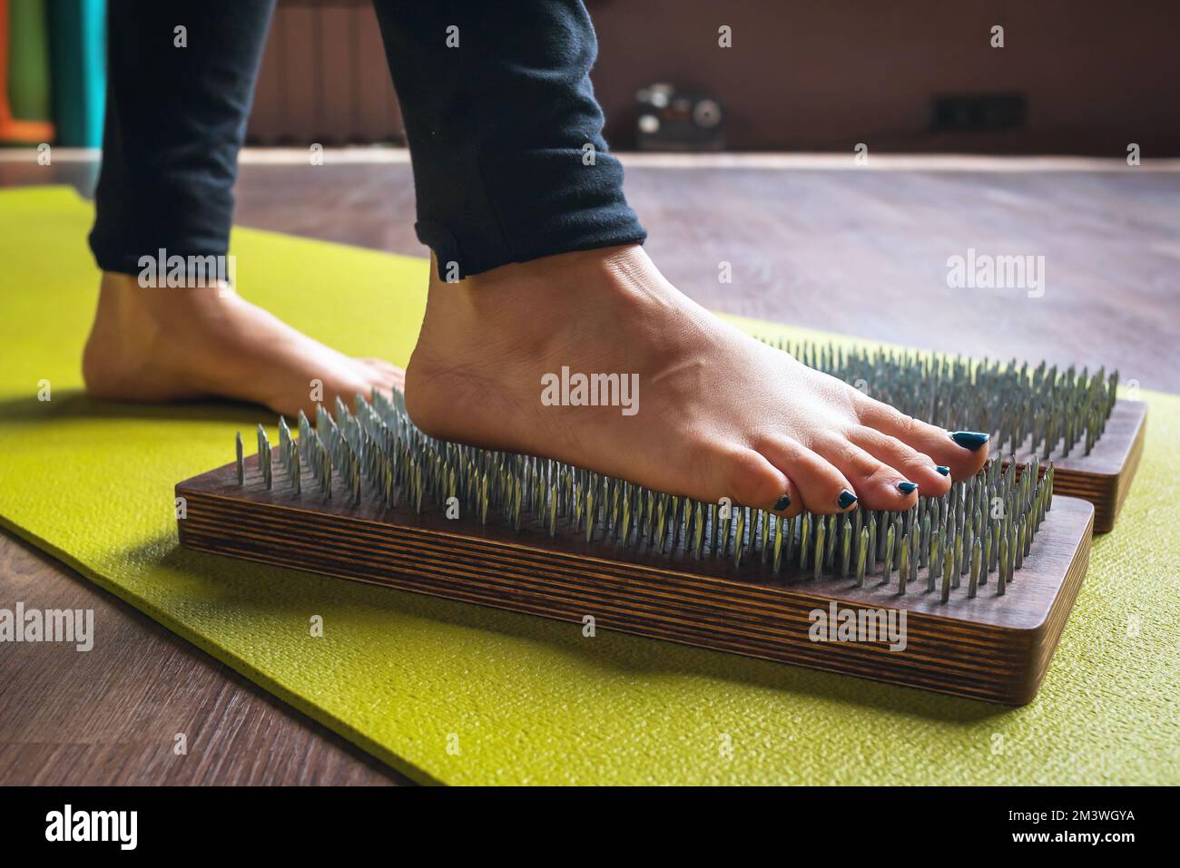 A woman practicing yoga steps on a sadhu board with nails, a concept on