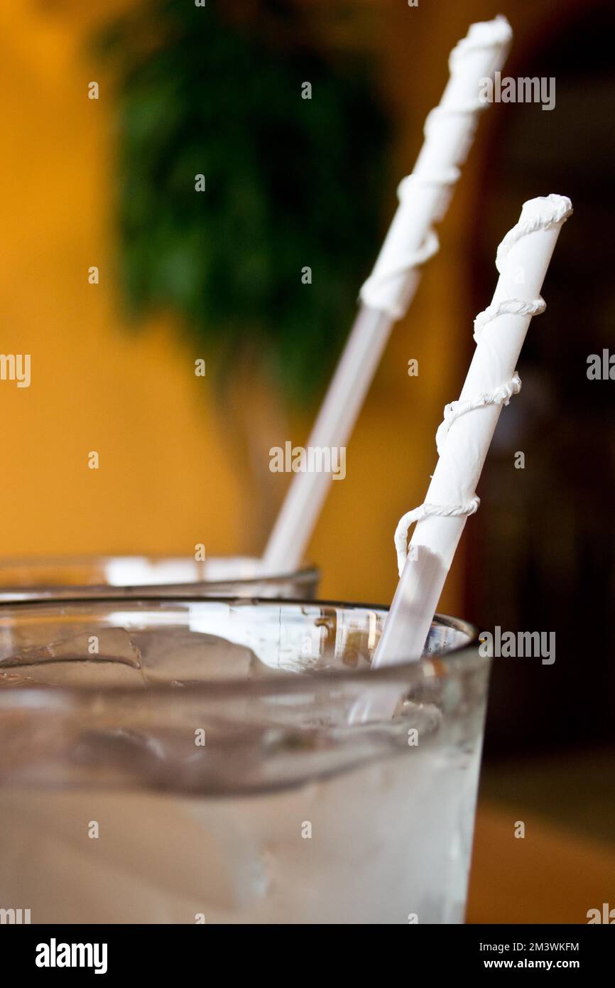 Glasses of ice water with straws with their paper wrapper twisted ...