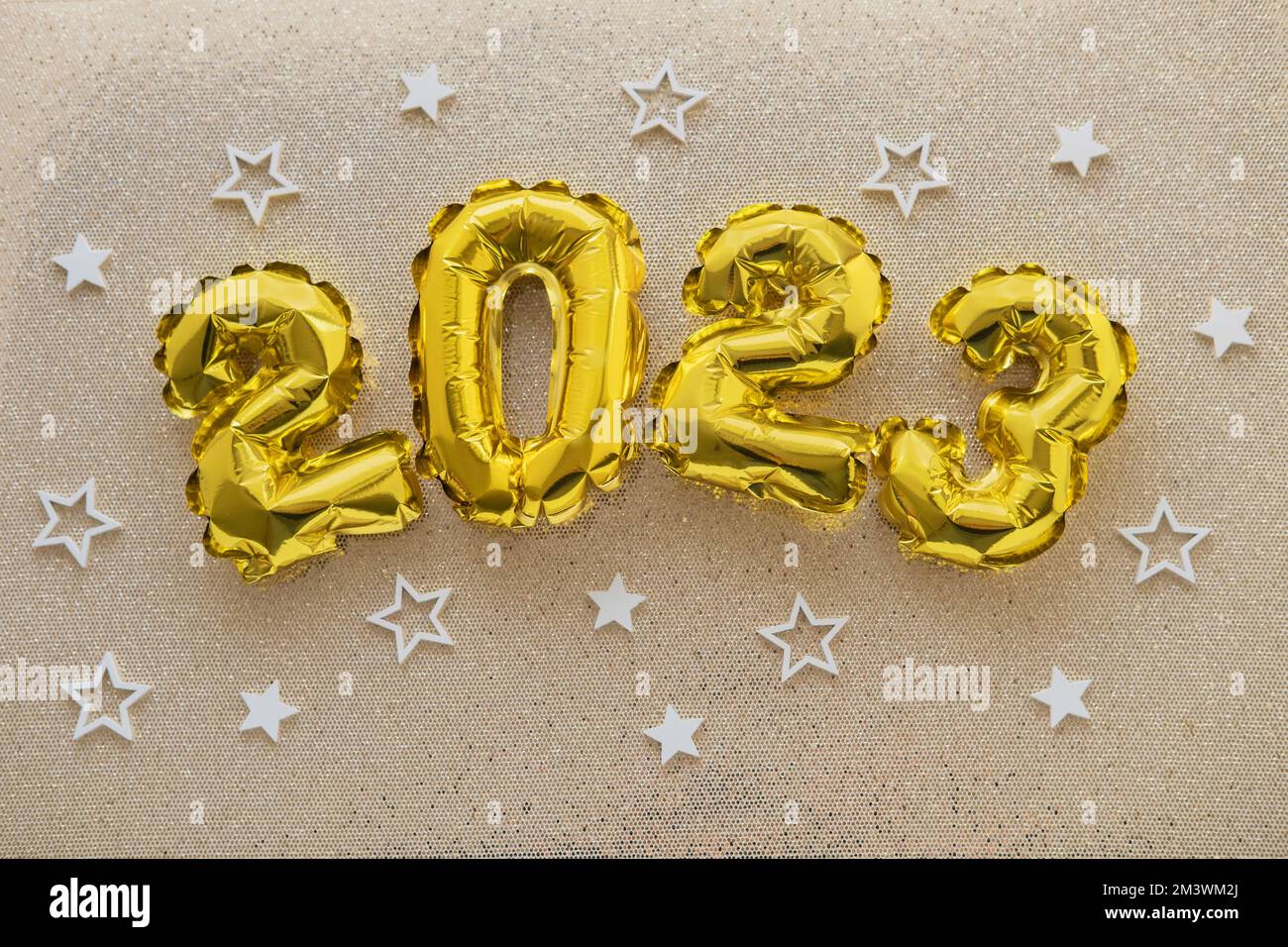 2023 gold foil balloons and confetti on gold glitter background. Festive concept. Stock Photo