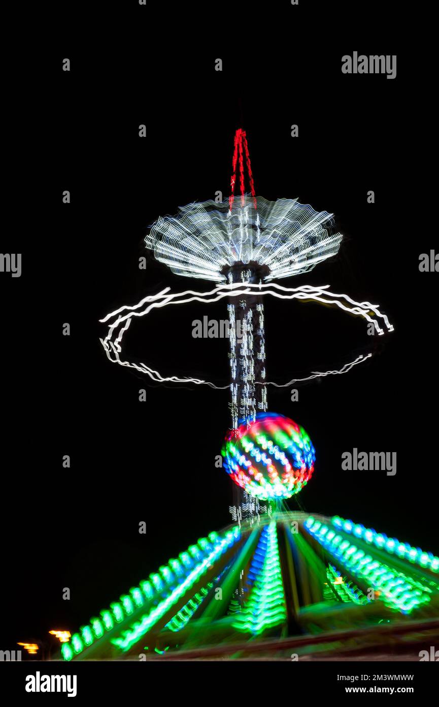 Rotating illuminated attraction in amusement park at night. Motion