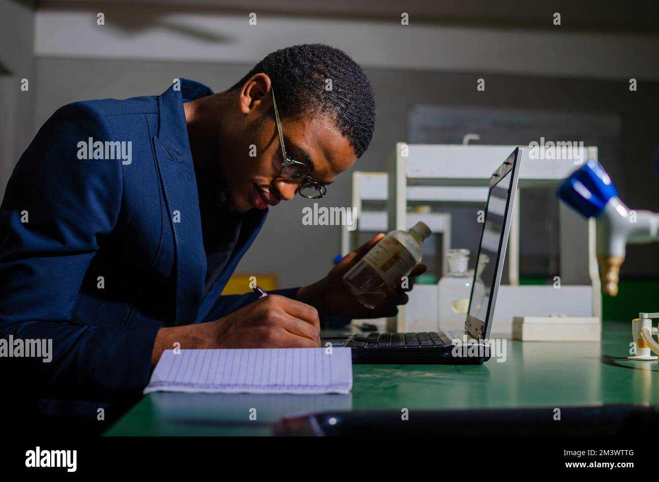 A pharmacist reviewing the list of drugs and checking the stock of all medicines at a lab Stock Photo