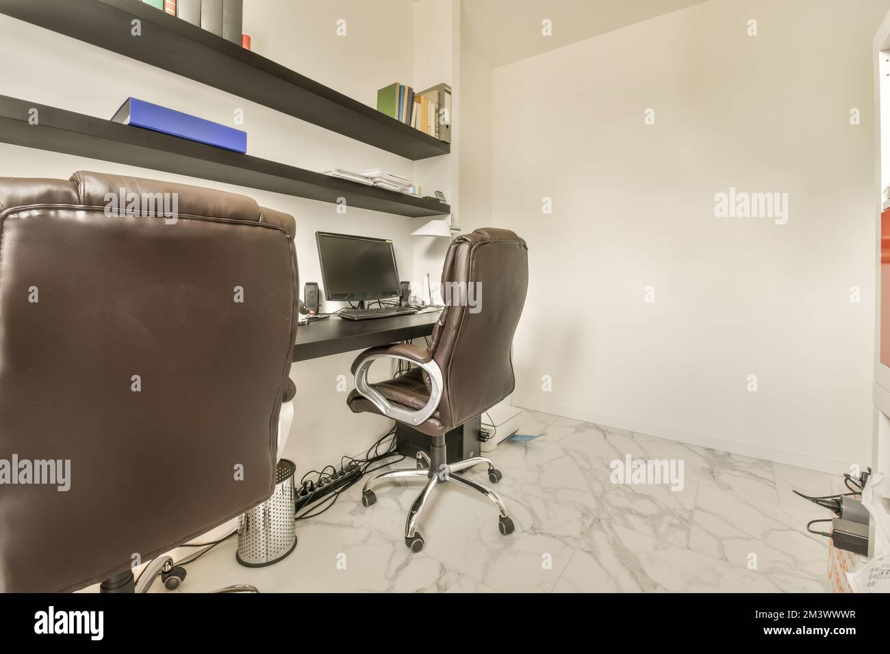 a home office with two brown leather chairs and a computer on the desk