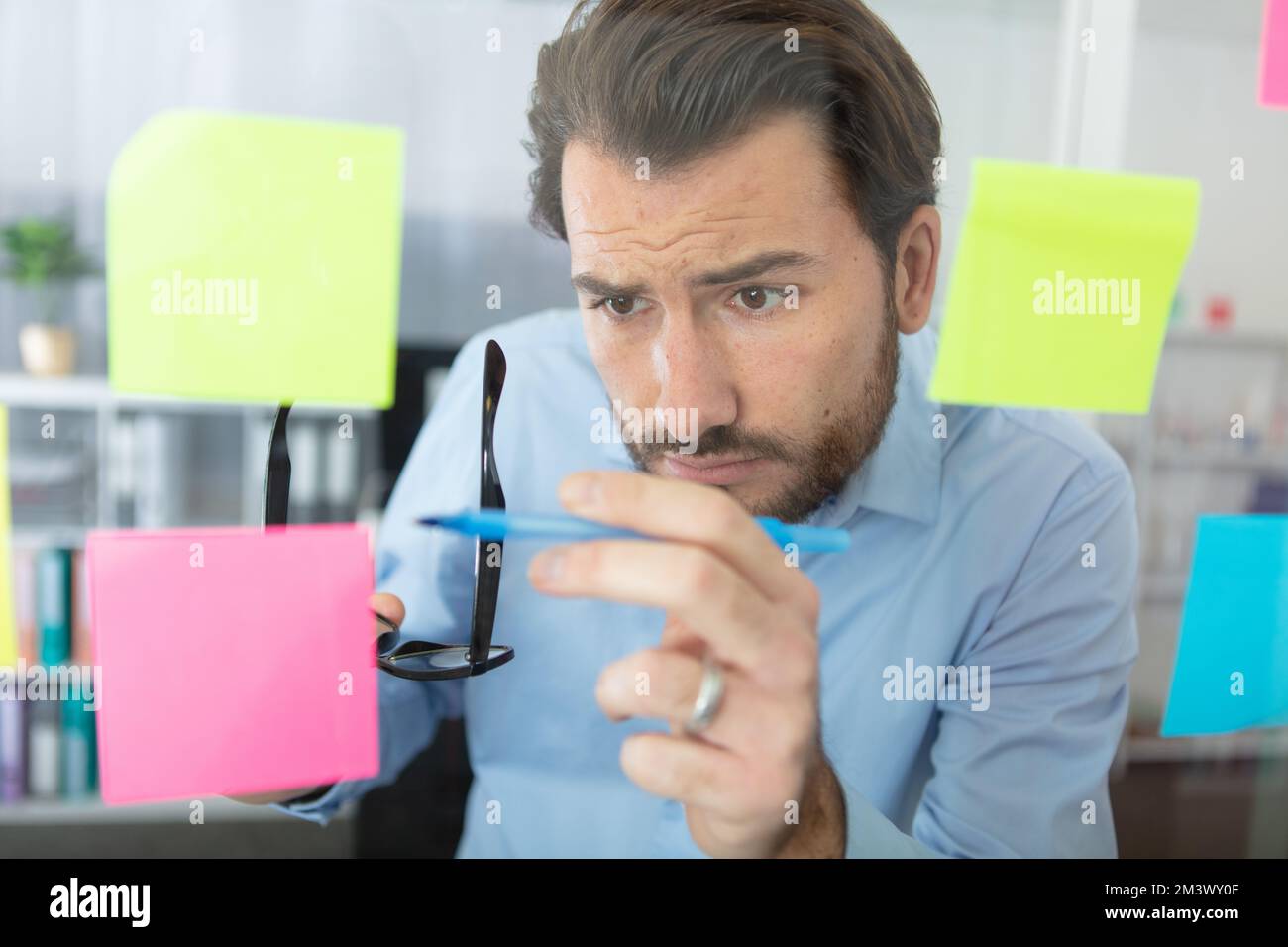 thoughtful man reading sticky notes in office Stock Photo