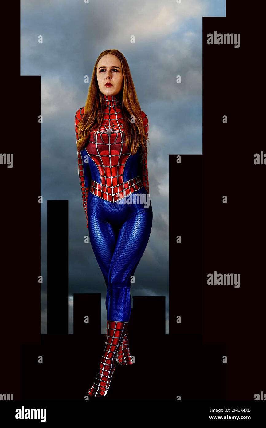 A young red haired woman in  a Spider-Man costume, cos play, standing against an abstract painted city background. Stock Photo