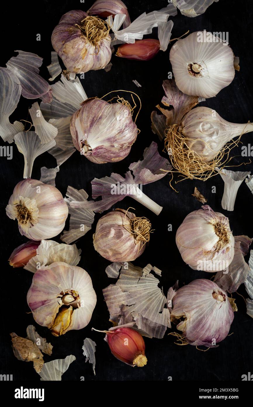 Fresh garlic bulbs and cloves grouped on black background. Flat lay ...