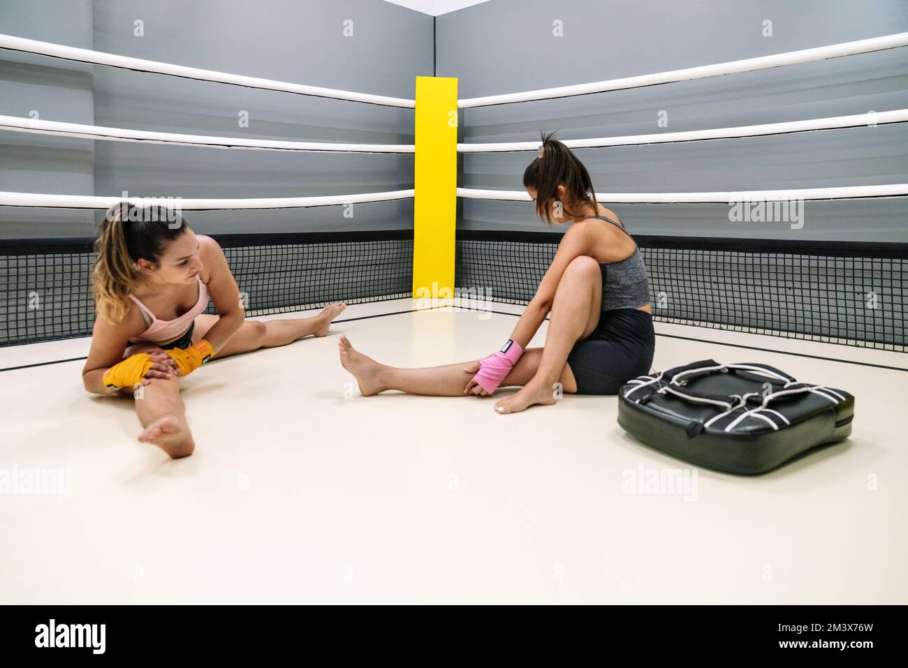 A young student practicing punching with her trainer in a kickboxing practice inside the ring Stock Photo