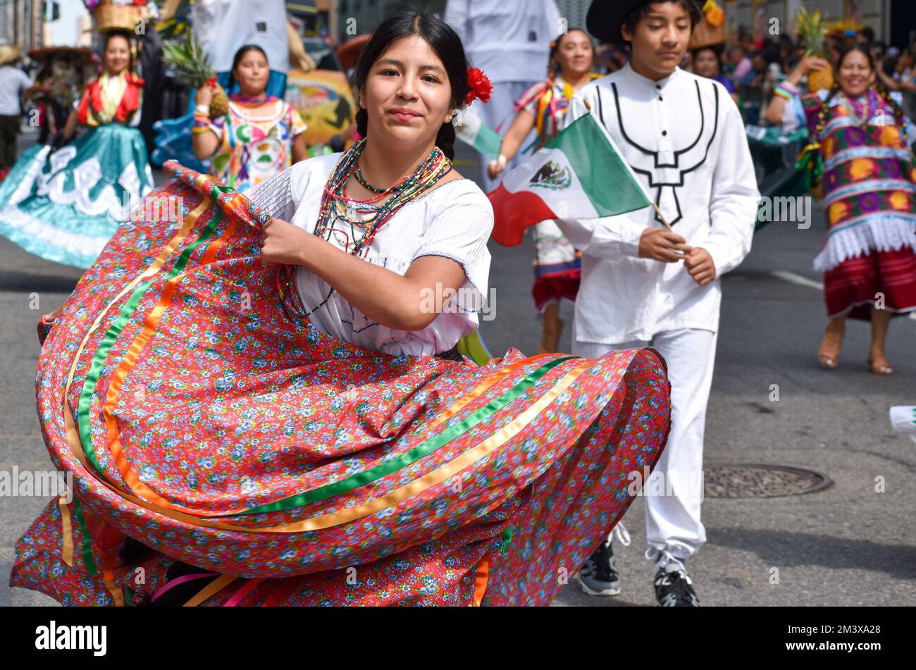 A smiling female dancing in a traditional costume during the Mexican ...