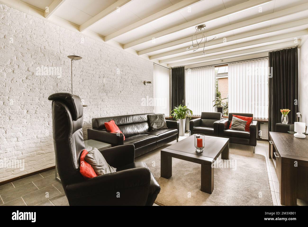 a living room with black leather couches and coffee table in front of