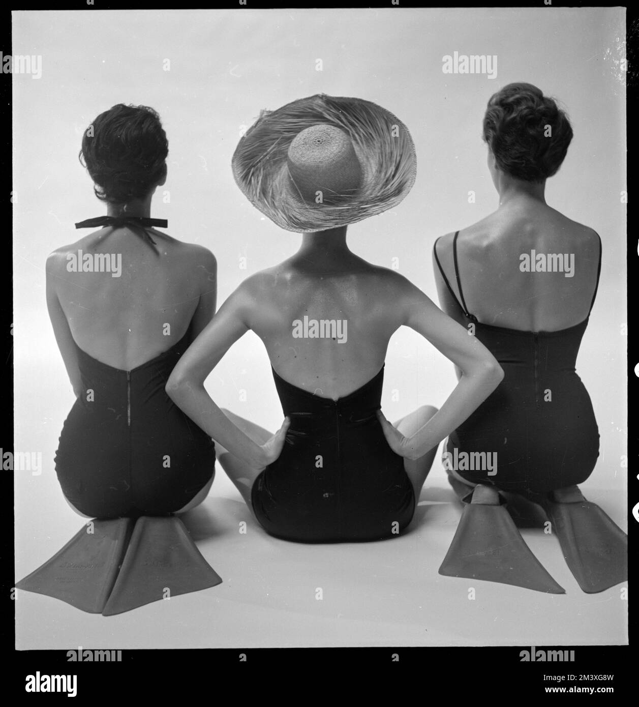 Back view of fashion models in swim suits, two kneeling wearing swim