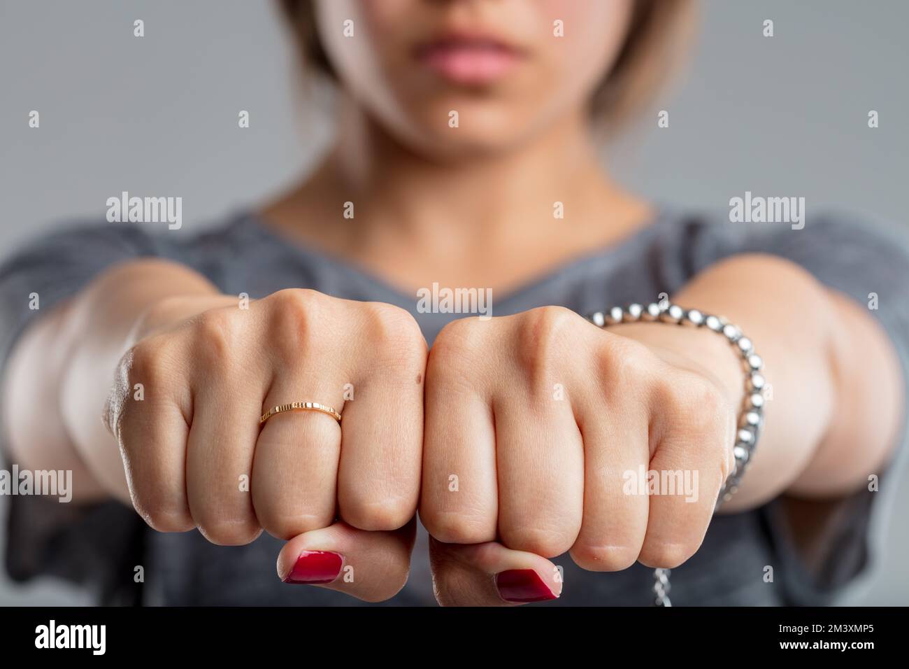 fists clenched together of a young woman. is this a sleight of hand and hiding something, or is it a threatening gesture? In any case, she is wearing Stock Photo