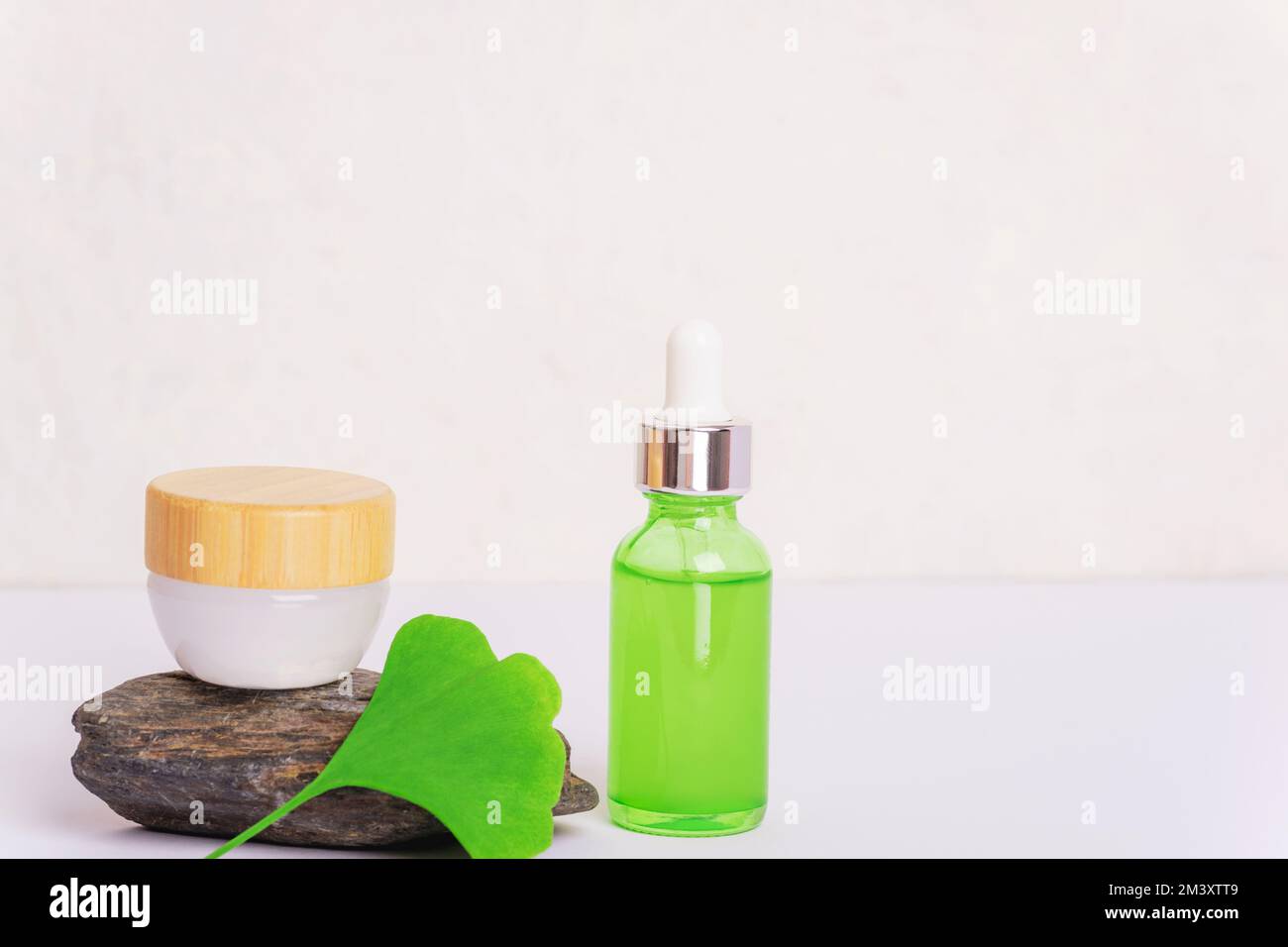 Fresh green ginkgo biloba leaf, cosmetic serum bottle and cream jar on white background. Closeup, copy space. Stock Photo