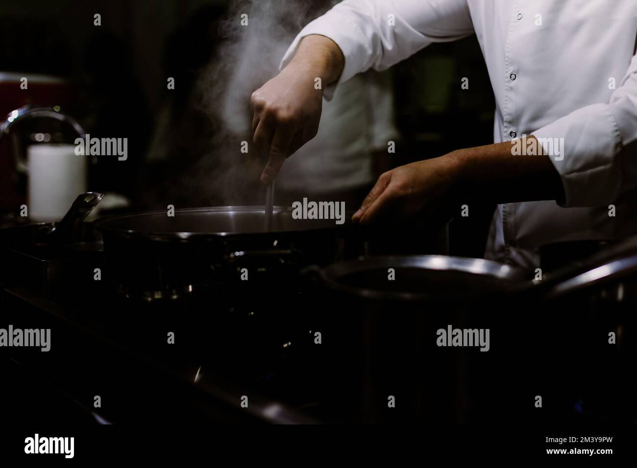 A cook stirring pots in the kitchen. Big pots in the kitchen. gastronomy education Stock Photo