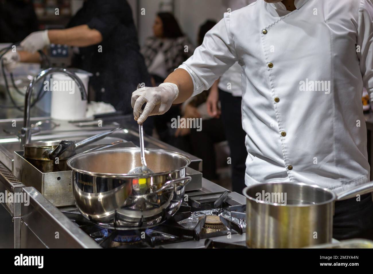 A cook stirring pots in the kitchen. Big pots in the kitchen. gastronomy education Stock Photo