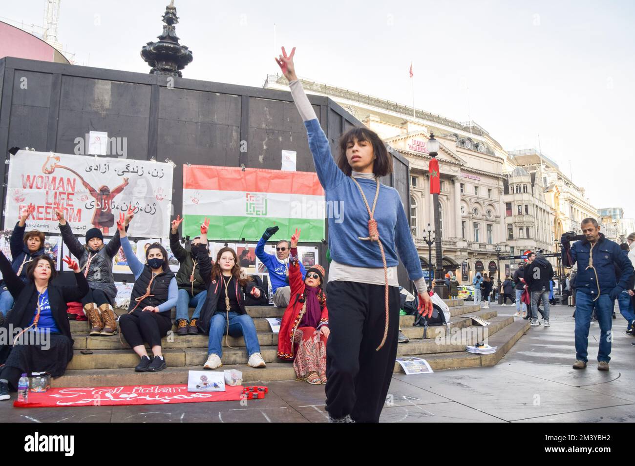 London, UK. 17th December 2022. A protester performs a dance with a noose around her neck. A group of women staged a demonstration and performance in Piccadilly Circus in protest against the reported executions of anti-government protesters in Iran. The activists tied ropes around their necks and covered their hands in fake blood. Credit: Vuk Valcic/Alamy Live News Stock Photo