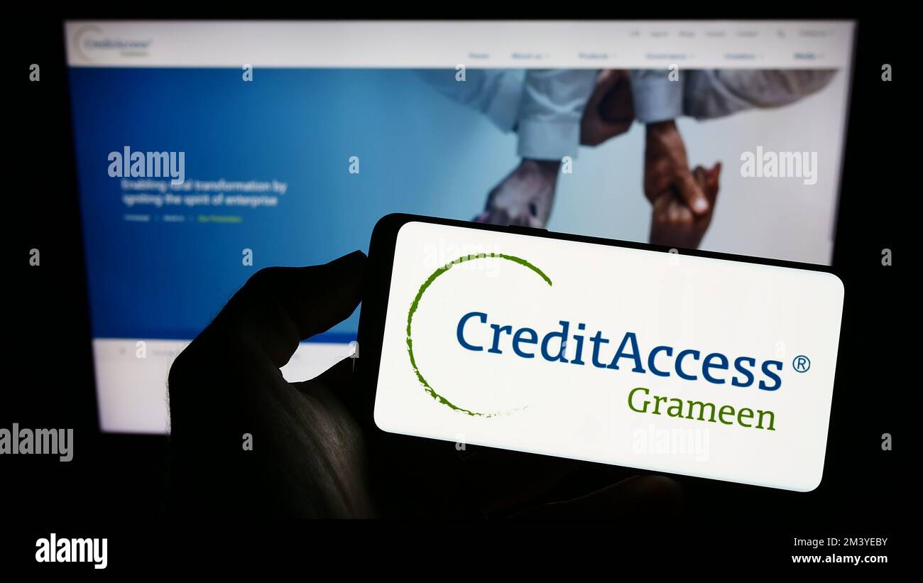 Person holding cellphone with logo of Indian company CreditAccess Grameen Limited on screen in front of business webpage. Focus on phone display. Stock Photo