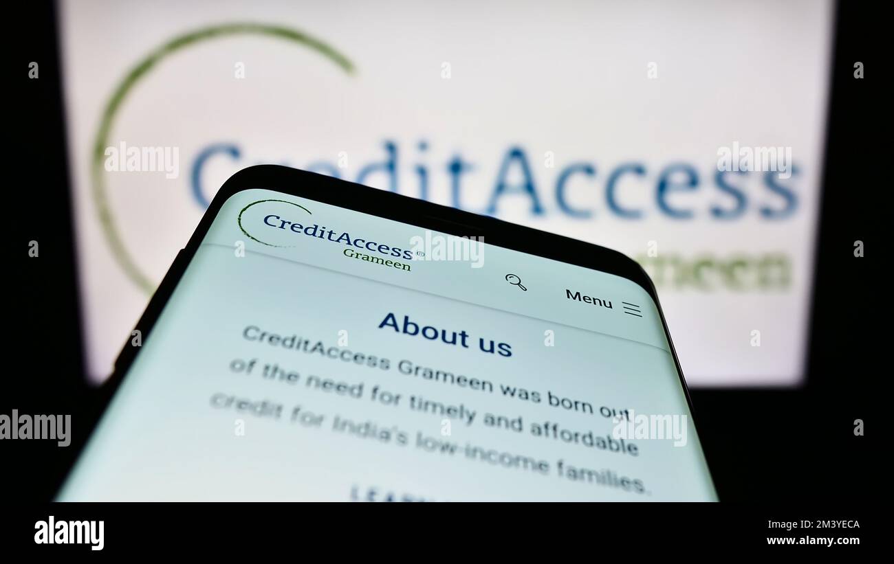 Mobile phone with website of Indian company CreditAccess Grameen Limited on screen in front of business logo. Focus on top-left of phone display. Stock Photo