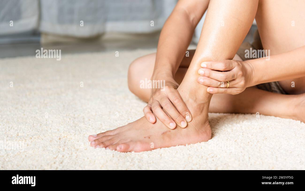 woman-holds-her-ankle-injury-feeling-pain-in-her-foot-at-home-stock