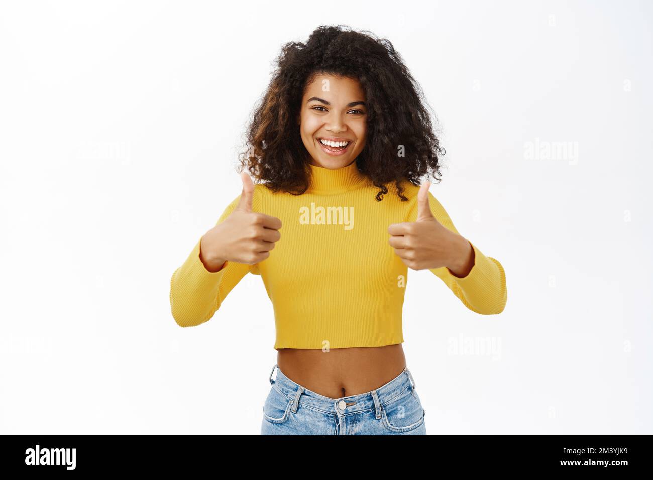 Smiling black girl showing thumbs up, looking satisfied, praise smth ...
